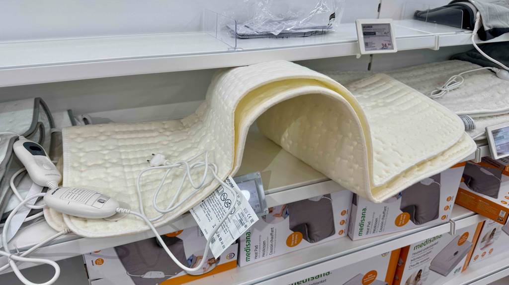 Das beigefarbene getestete Beurer-Wärmeunterbett liegt auf einem Verkaufsregal mit weiteren Wärmeunterlagen.