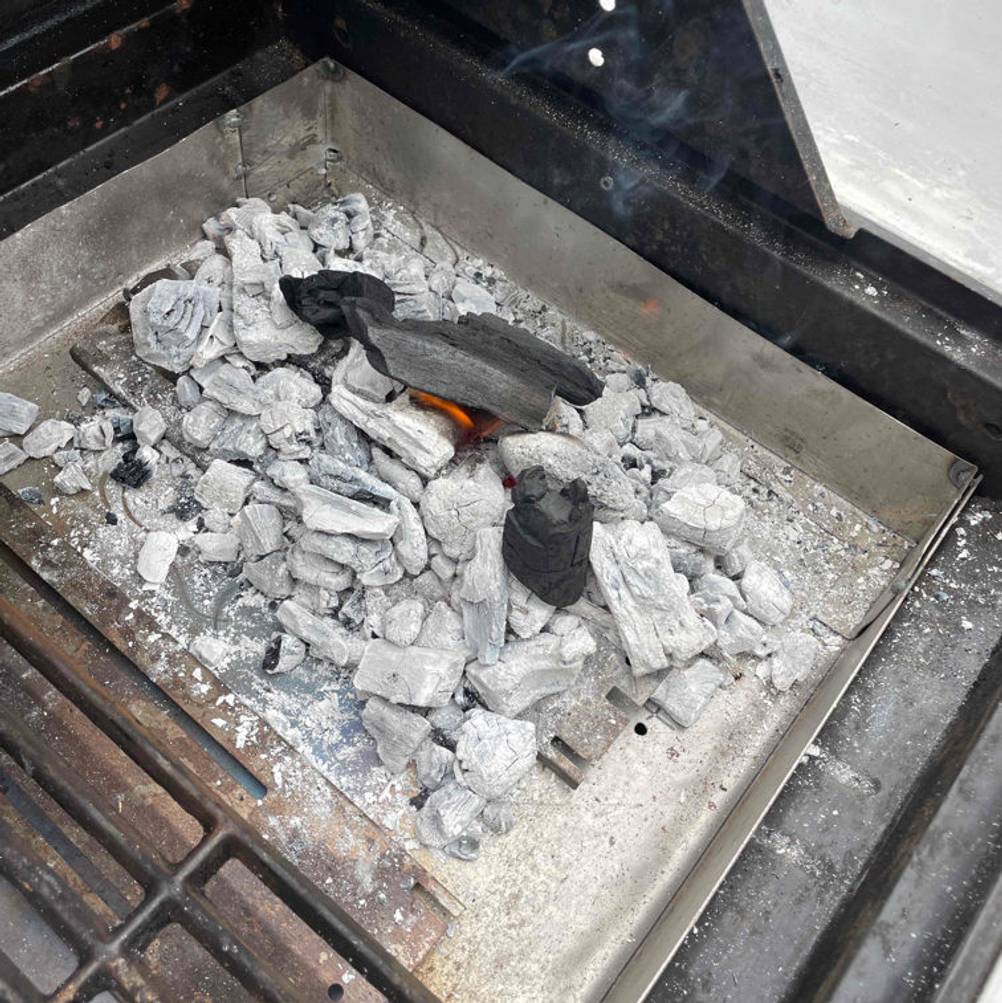 Grillkohle im Test: eine Grillkohle, die in einem Griller liegt, welche bereits angezündet wurde.