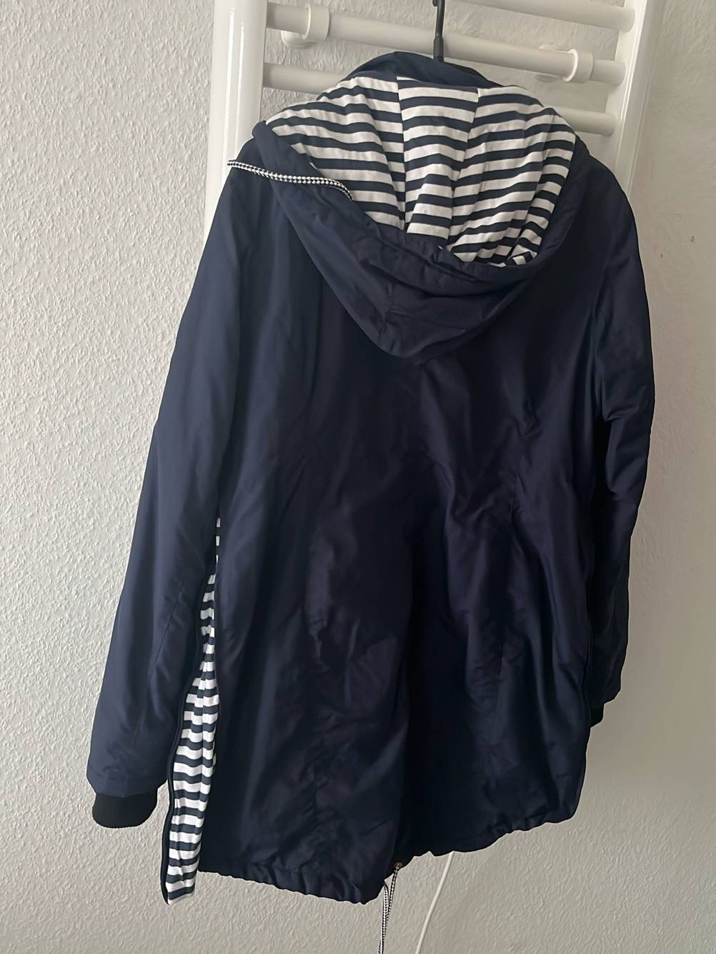 Tragejacke für Damen-Test: Rückseite einer Tragejacke für Damen auf einem Kleiderebügel hängend.