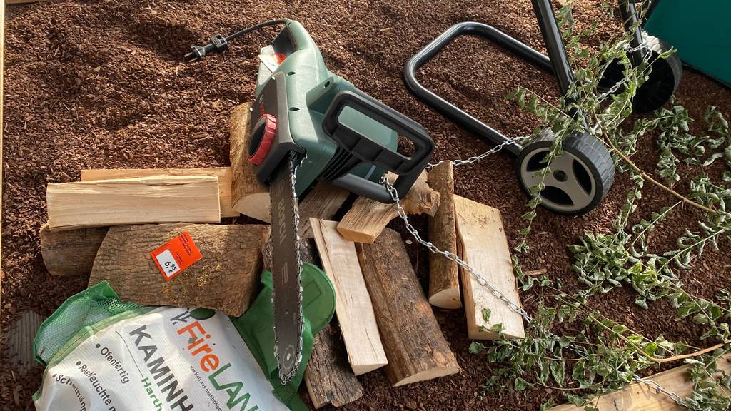 Auf einem Stapel Holz liegt eine getestete Elektro-Kettensäge vertikal.