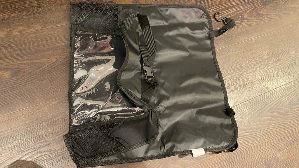 Rückenlehnenschutz-Test: ein schwarzer Rückenlehnenschutz mit verschiedenen Taschen liegt auf einem Boden.
