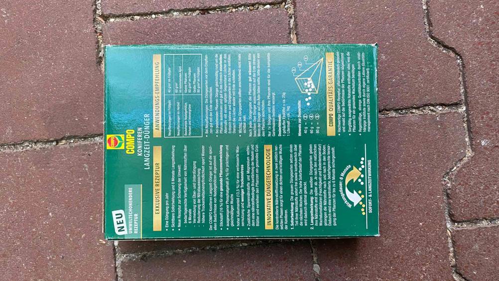 Koniferendünger im Test: Eine Packung liegt mit der Rückseite nach oben auf einem dunklen Boden