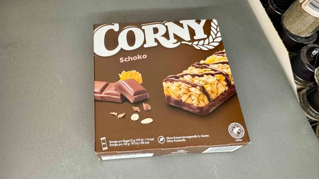 Test: Eine Packung Corny-Riegel mit 6 Stk darin liegt auf einer grauen Fläche.