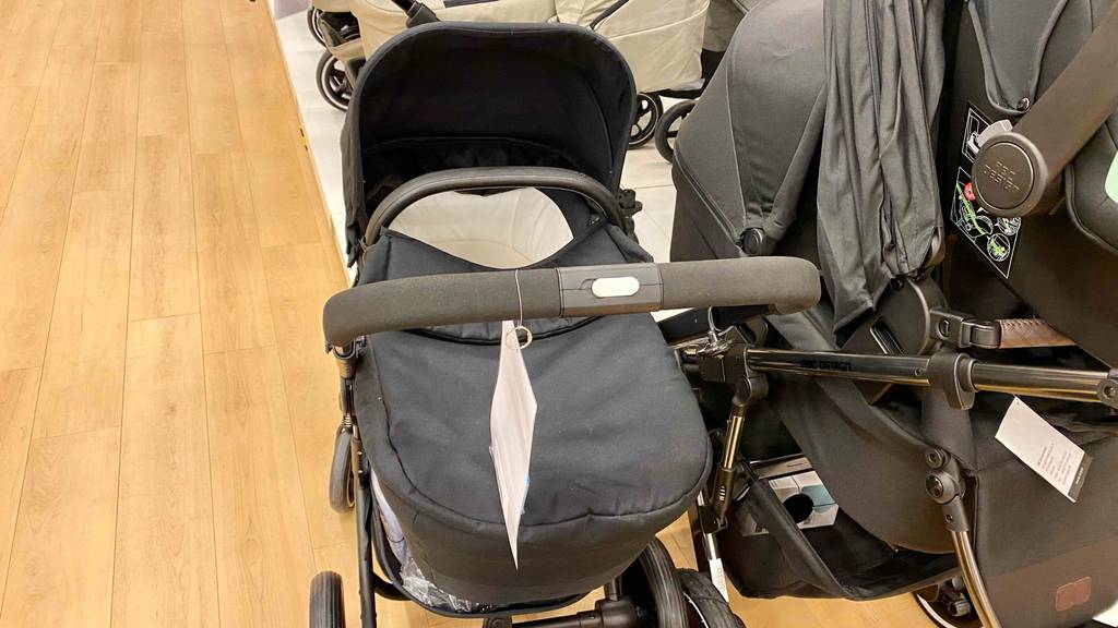 2-in-1-Kinderwagen im Test: ein 2-in-1-Kinderwagen mit dem Lenker und dem Wanneneinsatz ersichtlich in einem Geschäft stehend.