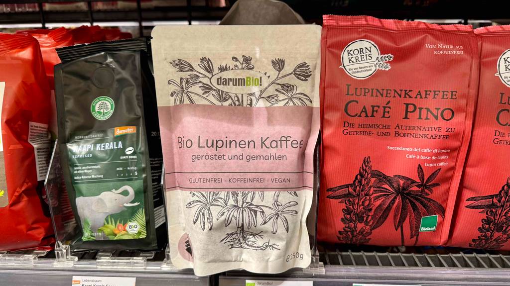 Test: Mehrere Packungen Lupinenkaffee verschiedener Marken sind in einem Regal einsortiert.