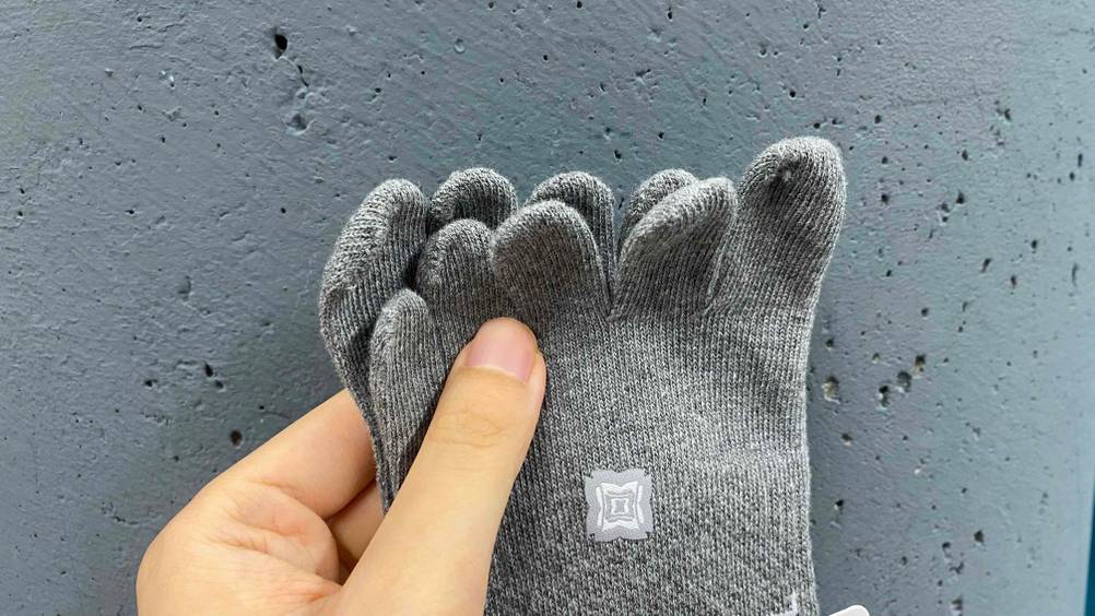 Eine Hand hält ein Paar getestete Yoga-Socken ganz vorne an den Zehen.