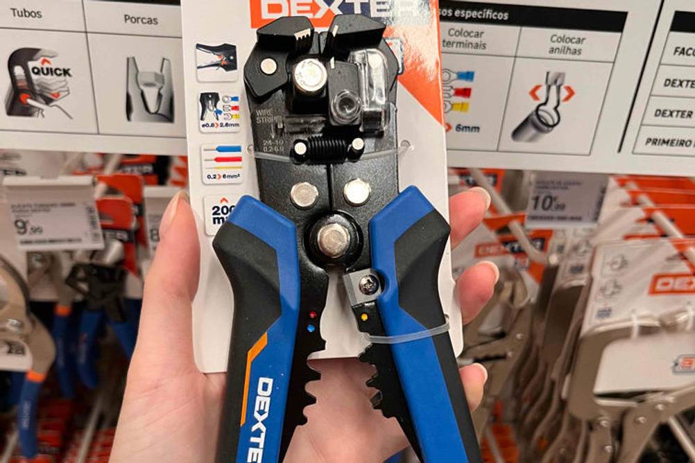 Automatische-Abisolierzange-Test: Abisolierzange mit blauem Griff wird in Verpackung in der Hand gehalten.