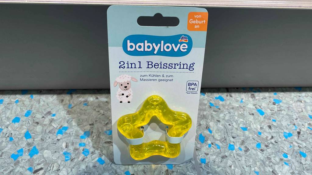 Beißring getestet: Ein verpackter Beißring lehnt an einer grauen Fläche.