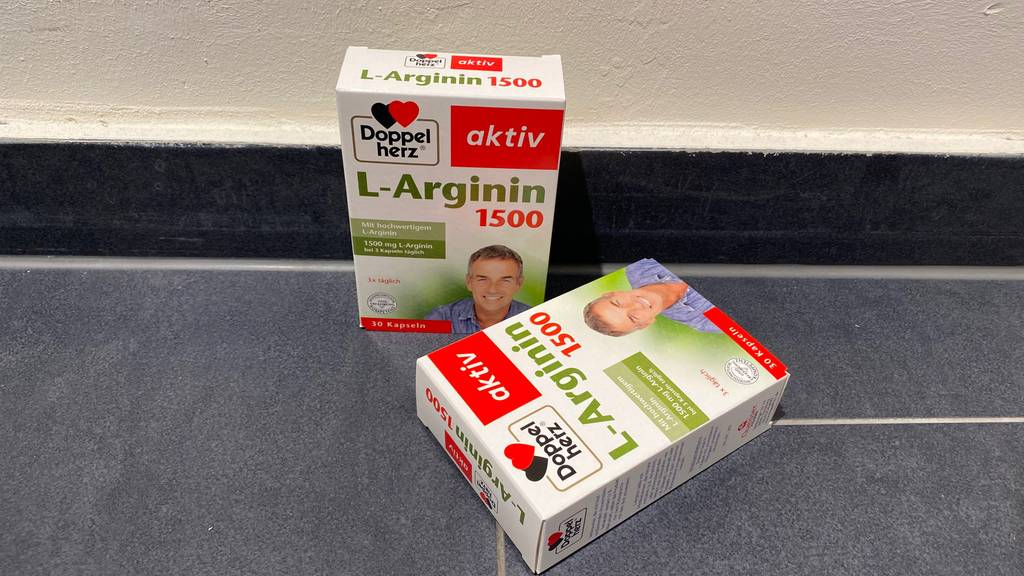 Im Test: Zwei Packungen L-Arginin auf einem grauen Fließenboden, eine stehend, eine liegend