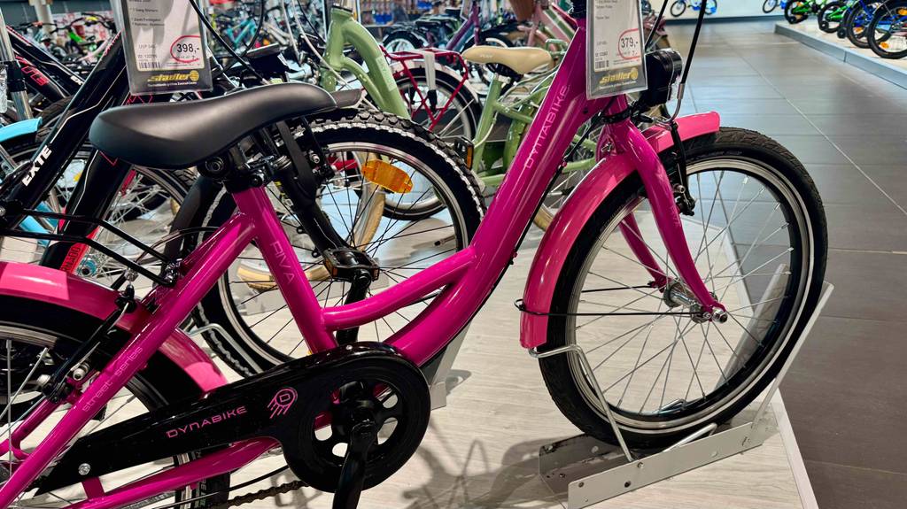 Getestet: Das Mädchenfahrrad 20 Zoll in Pink steht mit Fokus auf den Sattel und das Vorderrad auf einem Podest im Geschäft.