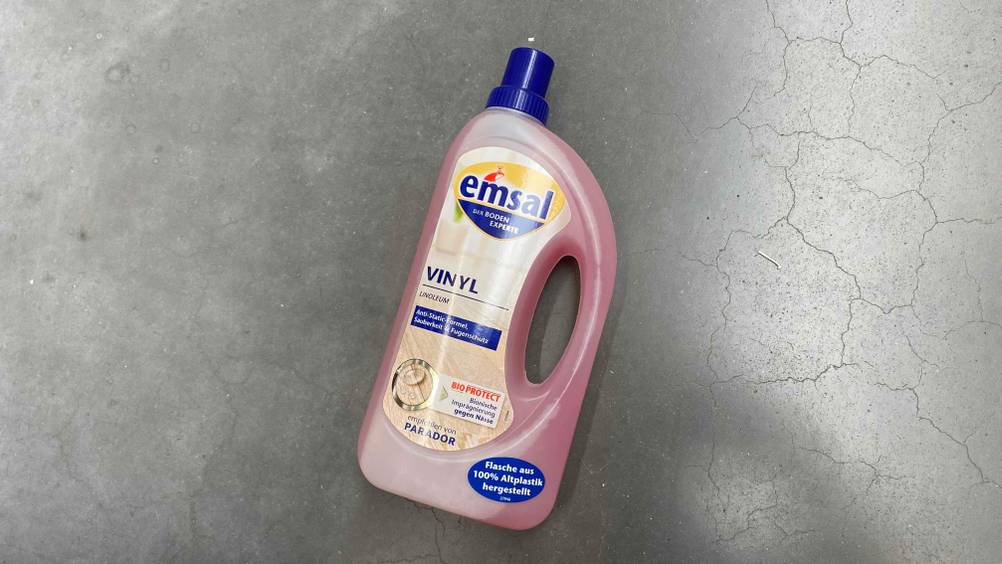 Auf einem grauen Boden liegt eine Flasche getestete Vinylboden Pflege