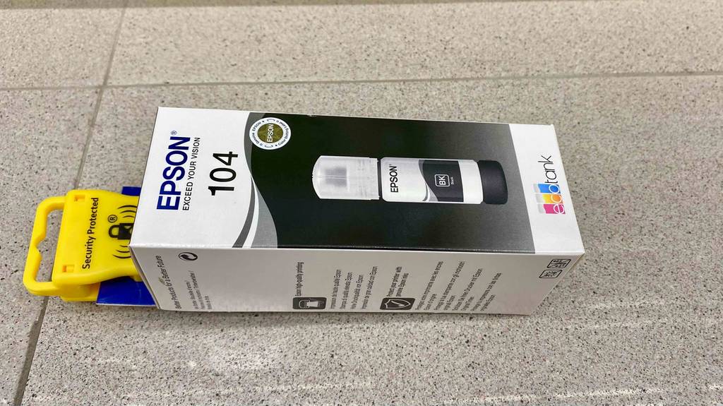 Im Test: Ein verpackter Epson-EcoTank von der Seite auf einem Fließenboden liegend.