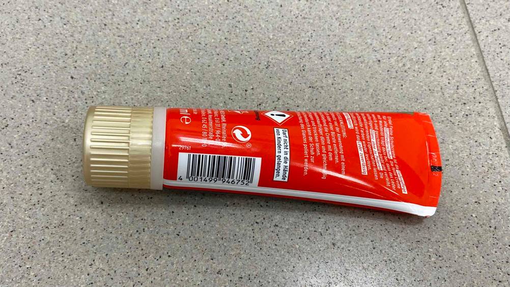 Schuhcreme im Test: Eine Tube liegt mit der Rückseite nach oben auf einer grauen Oberfläche
