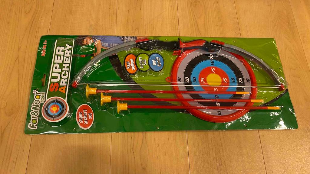 Pfeil und Bogen für Kinder getestet: Ein Set liegt horizontal auf einem Holzboden.