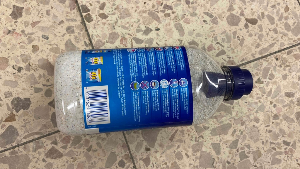 Im Test: Auf einem Fließenboden liegt eine Flasche Spülmaschinenpulver mit der Rückseite nach oben