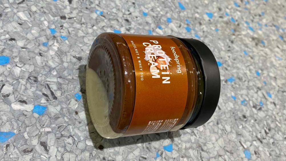 Protein Creme getestet: Ein Glas Protein Creme liegt auf der Seite auf einer Fließenoberfläche