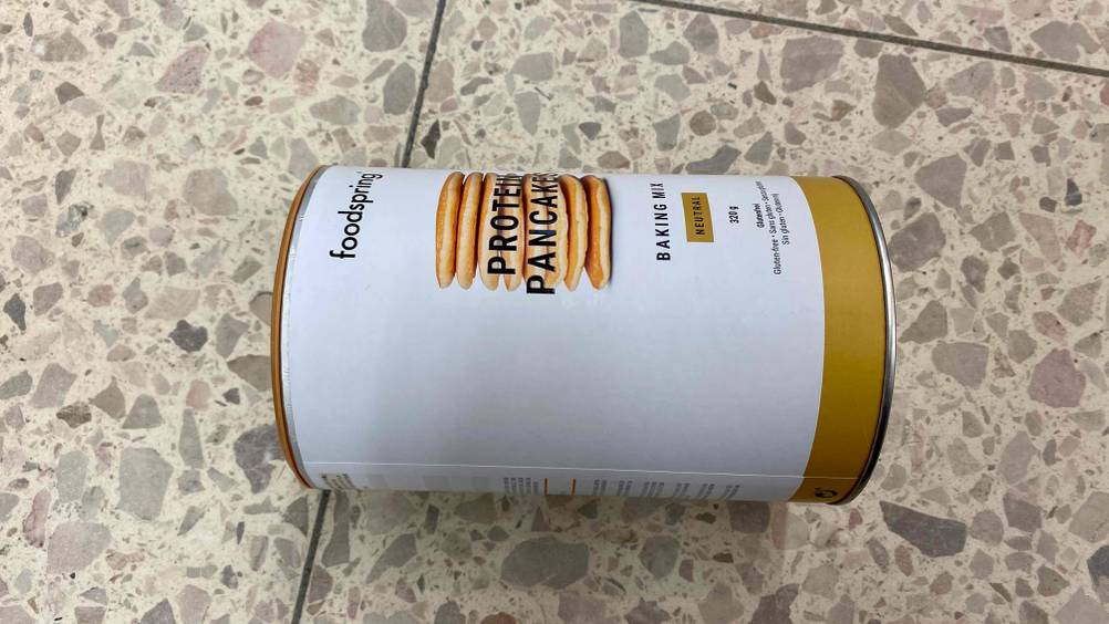 Protein Pancake im Test: Eine Dose Protein Pancake seitlich liegend auf einer Fließenoberfläche