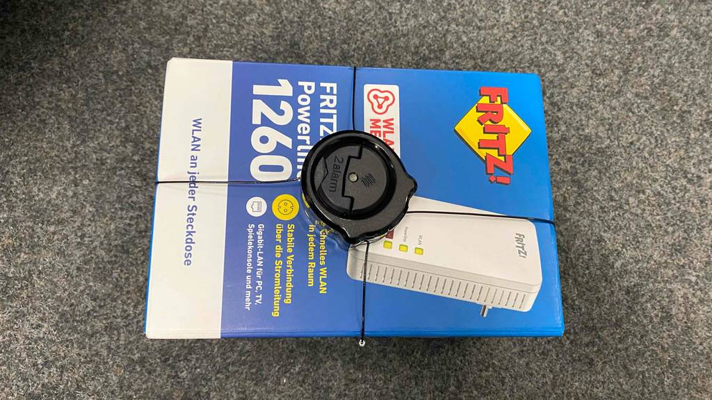 Ein getesteter Powerline-Adapter liegt originalverpackt auf einem grauen Teppich.