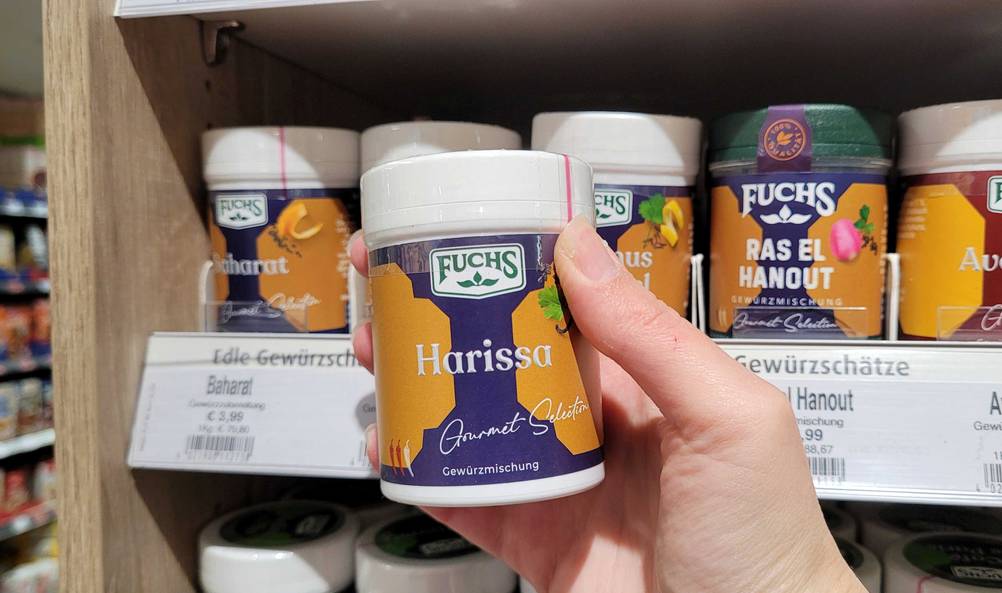 Harissa getestet: Eine Hand hält eine Dose vor ein Regal.