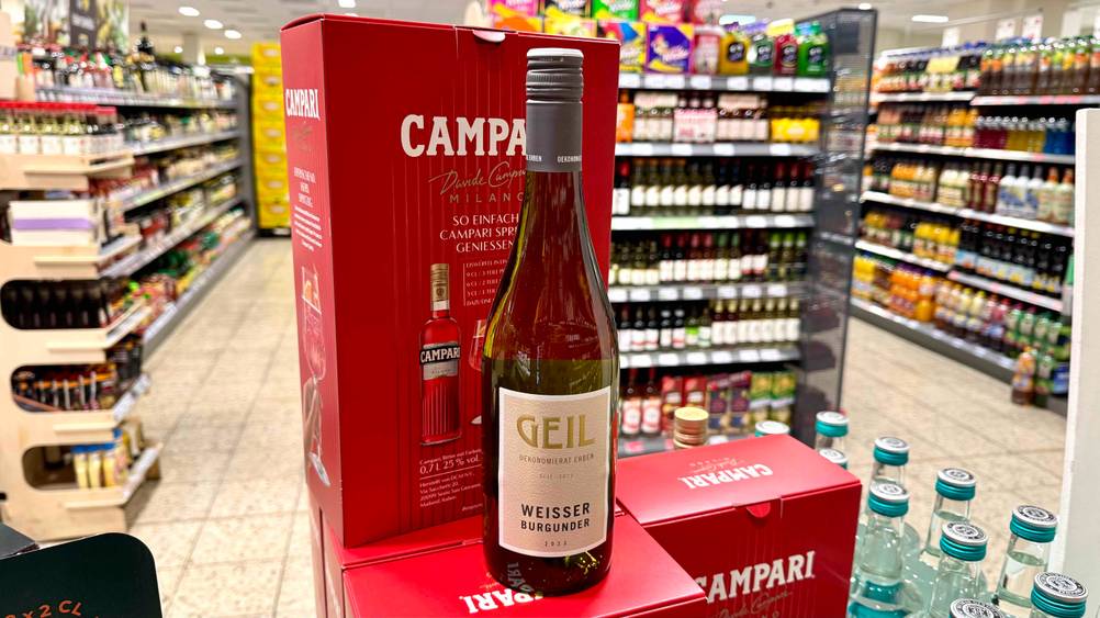 Die getestete Flasche Weißburgunder steht auf Kartons, in welchen sich Campari befindet.
