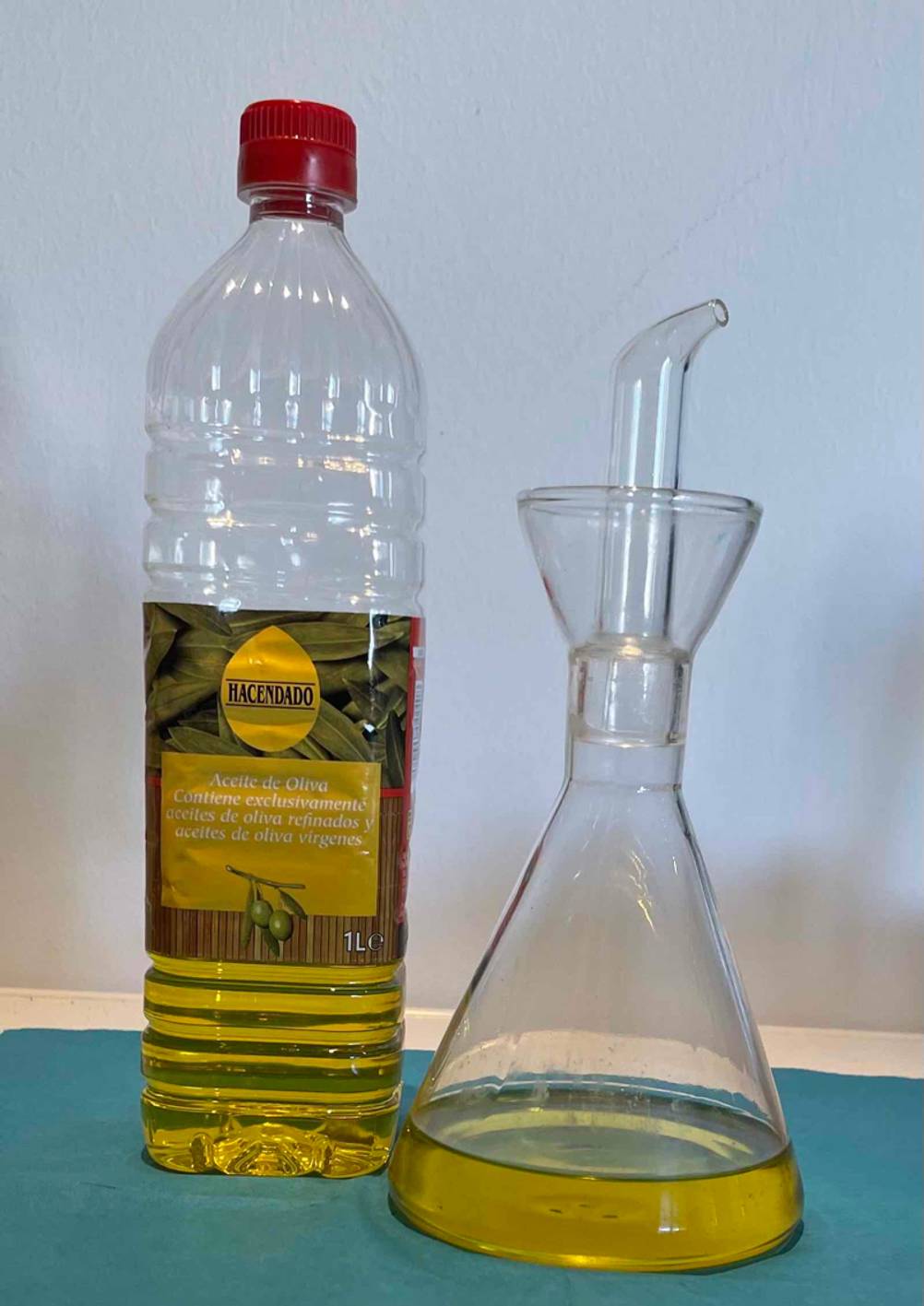 Spanisches-Olivenöl-Test: ein spanisches-Olivenöl steht neben einem Ölbehälter aus Glas.