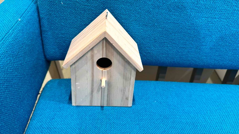 Das getestete Vogelhaus steht auf einer blauen Sitzfläche.