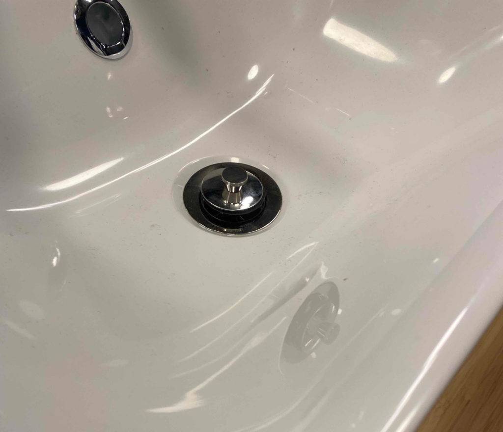 Waschbecken im Test: Abfluss eines weißen Waschbeckens im Fokus.