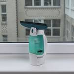 Der 2-in-1-Fenstersauger steht aufrecht auf einer weißen Fensterbank.