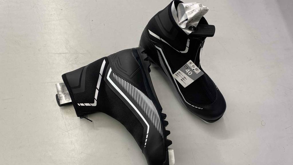 Langlaufschuh im Test: ein Paar Langlaufschuhe in Schwarz mit weißen Elementen - einer davon steht und der andere liegt auf der Seite.