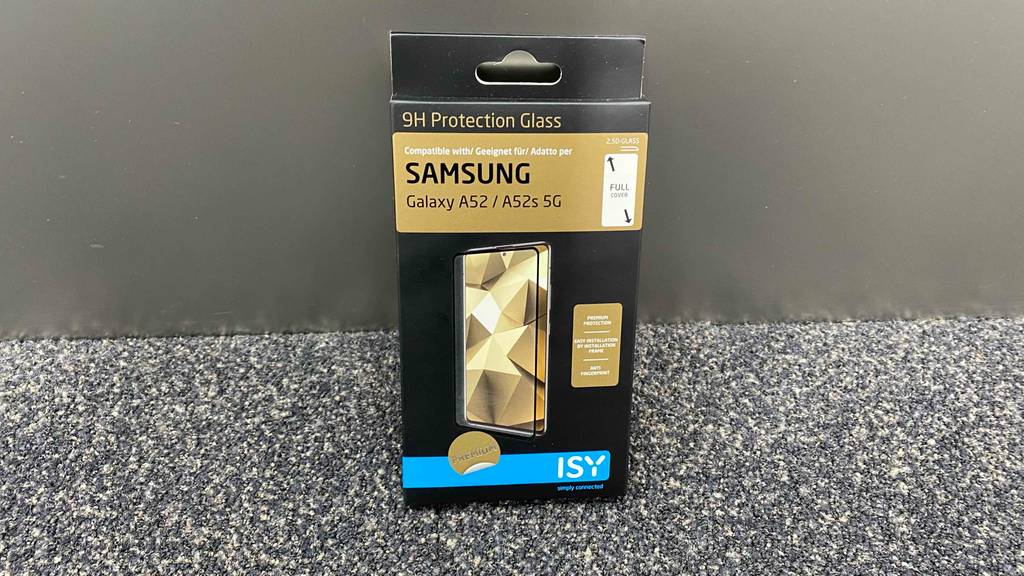 Ein getestetes Samsung-Galaxy-A52-Panzerglas in Originalverpackung lehnt an einer grauen Wand.