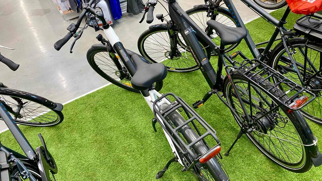 Jeep-E-Bike im Test: ein Jeep-E-Bike, das mit einem Gepäckträger ausgestattet ist, steht neben anderen Modellen in einem Geschäft.