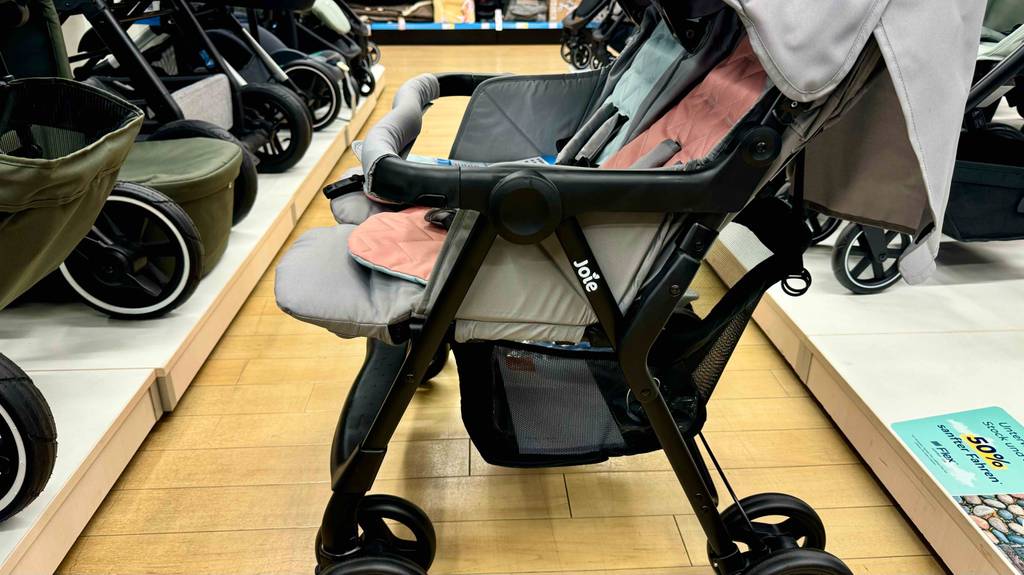 Der getestete Zwillingskinderwagen steht in einem Geschäft, der mit einem Aufbewahrungskorb ausgestattet ist.