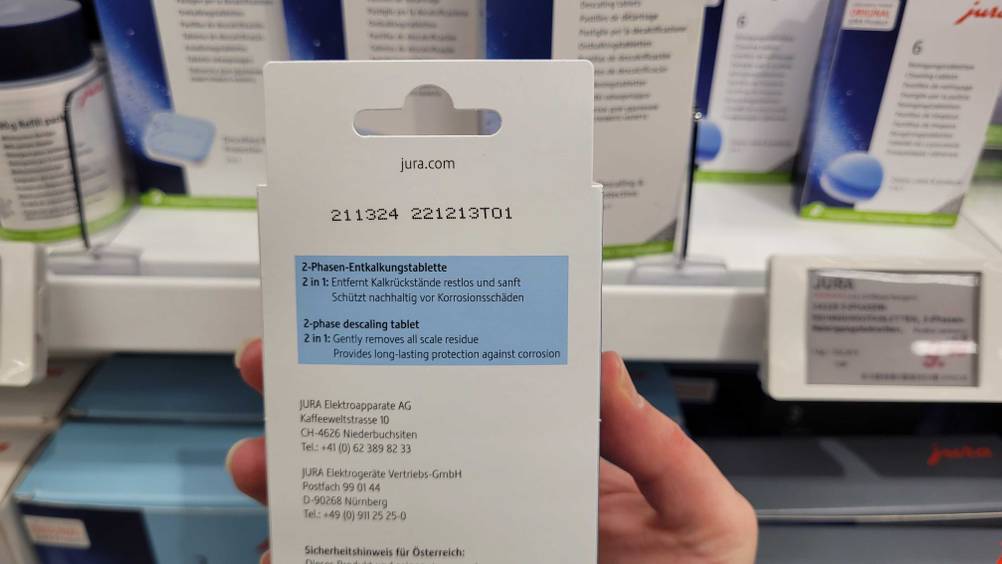 Entkalkungstabletten-Kaffeevollautomat im Test: die Verpackung wird mit der Rückseite ersichtlich in der Hand gehalten, worauf man Informationen zum Produkt findet.