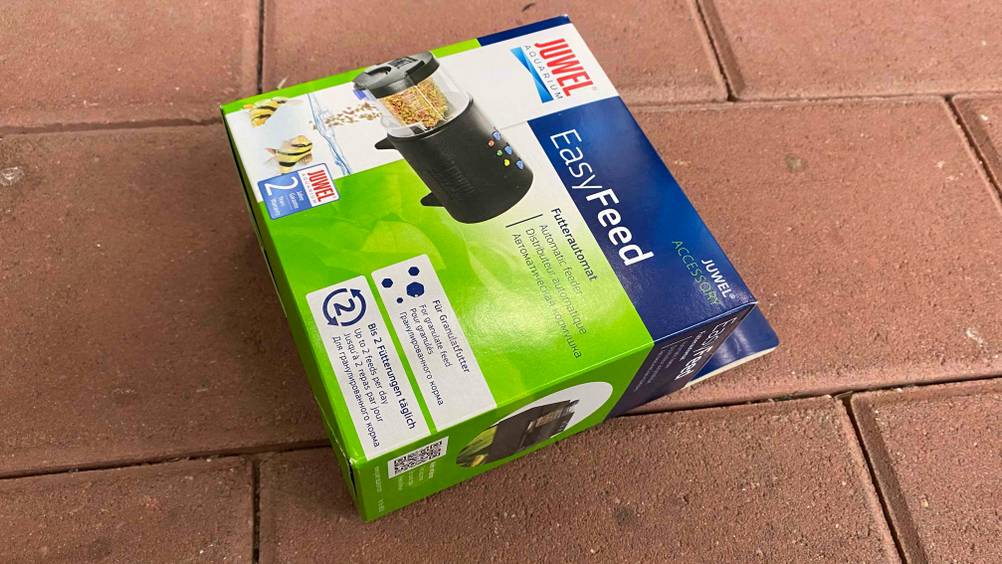 Futterautomat-Aquarium getestet: ein Futterautomat der Marke Juwel in einer Verpackung liegend auf einem Steinboden.