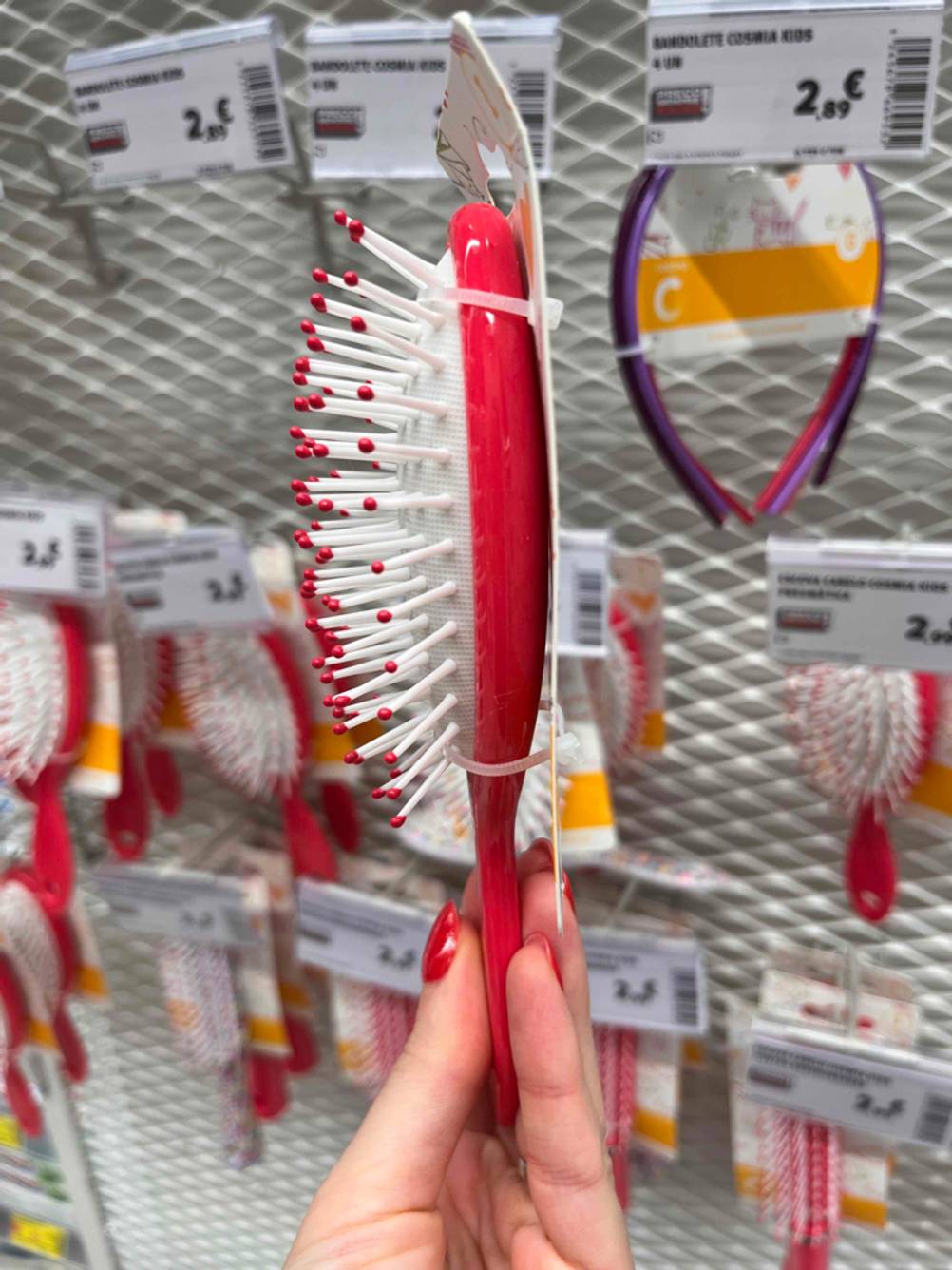Kinder-Haarbürsten im Test: eine Kinder-Haarbürste wird mit der Seite ersichtlich vor einem Regal gehalten.