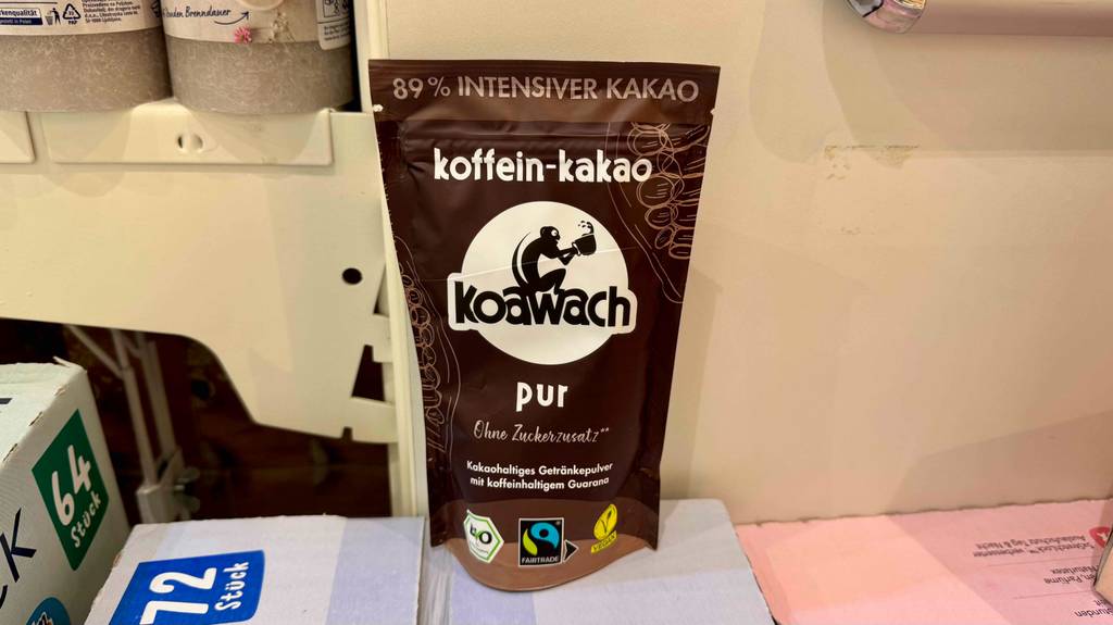 Das getestete Kakaopulver ohne Zucker steht innerhalb der wiederverschließbaren braunen Kunststofftüte auf einem weißen Lebensmittelkarton.