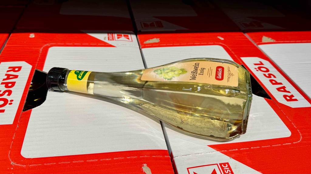 Eine getestete Flasche Weißweinessig in Nahaufnahme liegt auf Kartons.