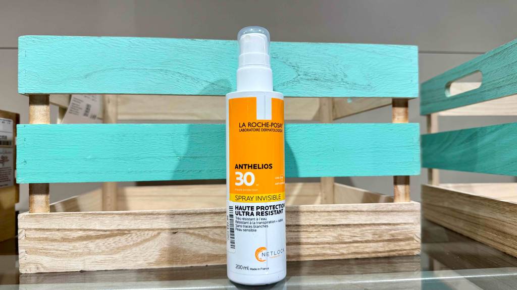 Eine getestete La-Roche-Posay-Sonnencreme steht in der Sprühflasche aus Kunststoff vor einer türkisfarbenen Holzkiste.