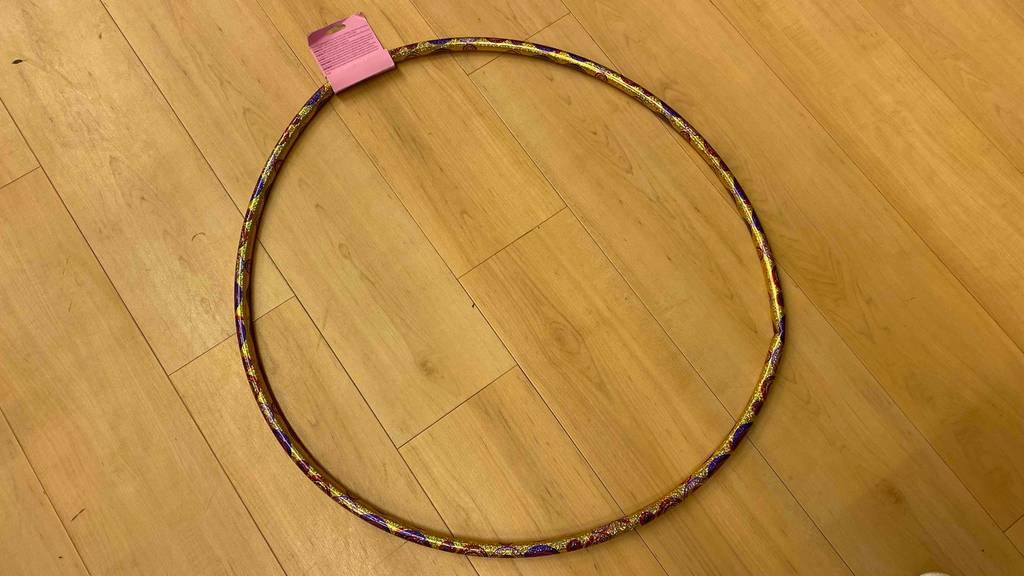 Hula-Hoop-Reifen für Kinder getestet: Ein Reifen liegt auf einem Holzboden.