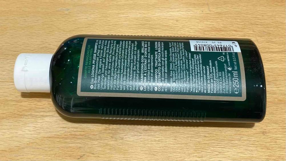 Im Test: Eine Flasche Brennnessel-Shampoo liegt mit der Rückseite nach oben auf einer Holzfläche.
