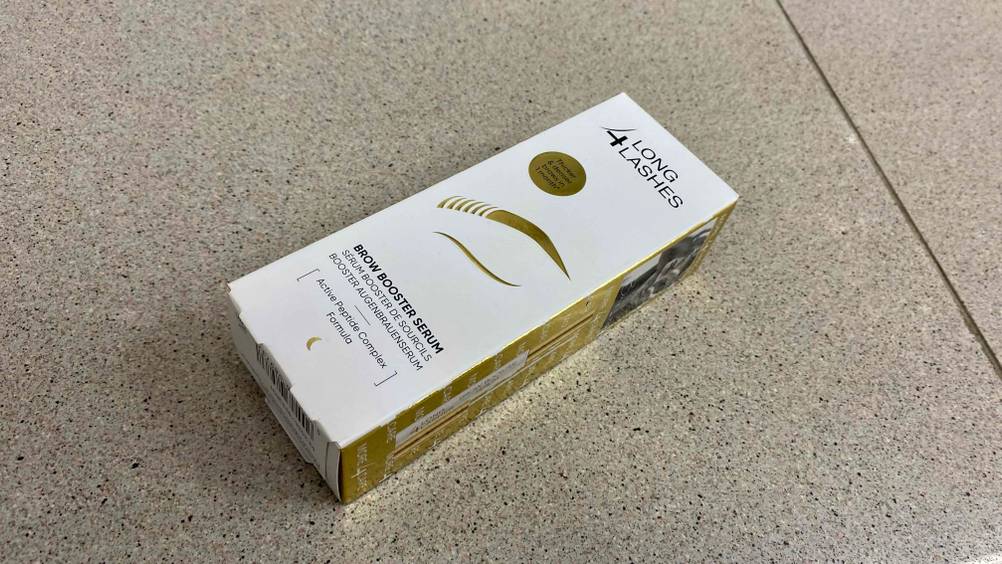 Augenbrauenserum im Test: Eine Packung Augenbrauenserum von der Vorderseite ersichtlich auf einem Fliesenboden liegend.