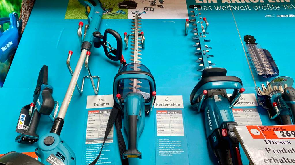 Makita-Akku-Heckenschere-Test: mehrere Heckenscheren sind an einer Wand zur Ausstellung befestigt.