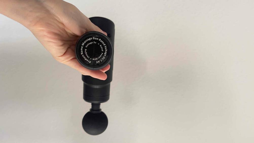 Mini-Massagepistolen im Test: Ansicht auf die Produkinformation des schwarzen Modells, das von einer Hand gehalten wird.
