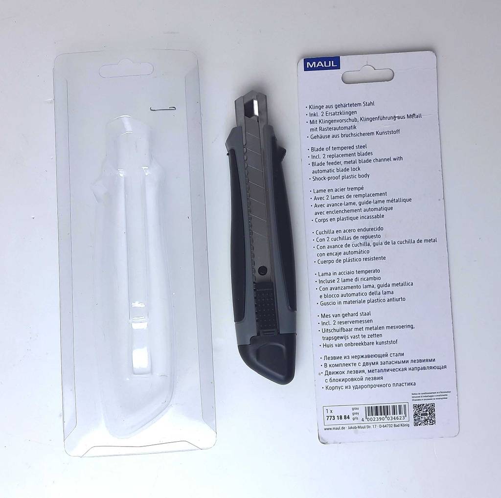 Teppichmesser-Test: Das dunkelgraue Modell liegt inmitten der geöffneten Verpackung auf einer weißen Oberfläche.