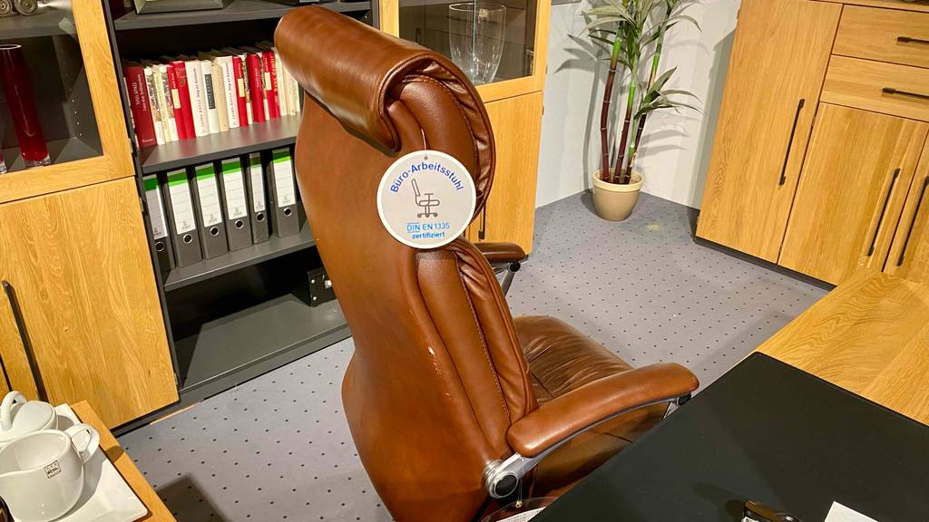 Chefsessel getestet: ein Chefsessel von der Seite ersichtlich mit einem Schild, worauf ersichtlich ist, dass das Modell DIN EN 1335 zertifiziert ist.