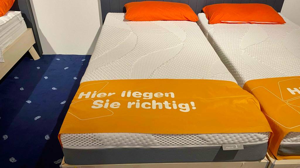 Eine getestete Latexmatratze in einem Doppelbett mit roten Kissen.