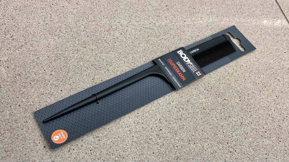 Im Test: Ein Toupierkamm liegt quer auf einer grauen Fläche.