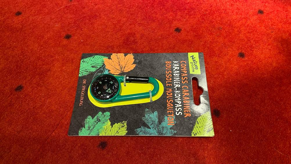 Kompass getestet: Auf einer roten Fläche liegt ein verpackter Kompass.