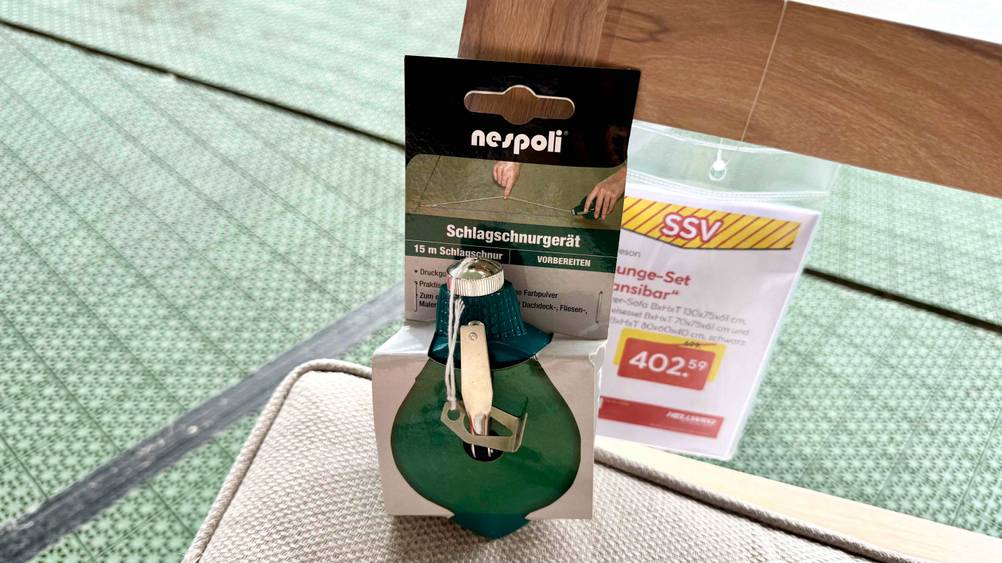 Die Schlagschnur mit 15 m Länge, welche getestet wurde, befindet sich noch in der Verpackung und lehnt am Rahmen einer Sitzgelegenheit.