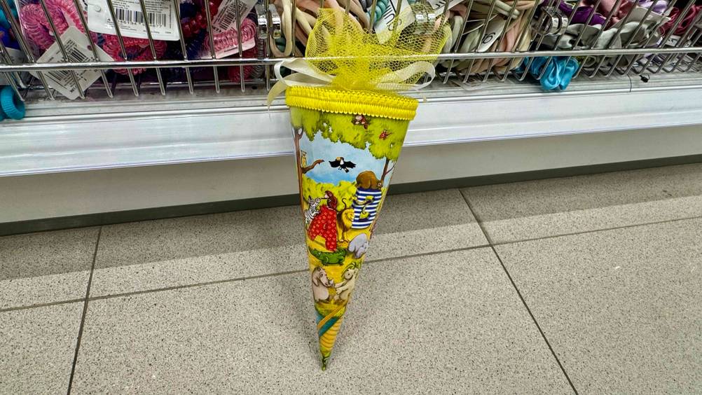 Die getestete kleine Schultüte mit Buchstaben und Tieren als Motiv lehnt an einem Regal.
